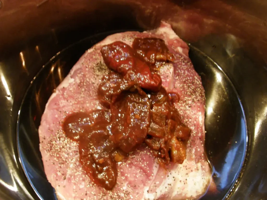 raw pork roast in pressure cooker with chipotle peppers and adobo sauce